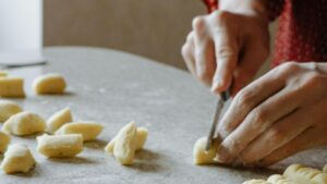 Mani di madre e figlia che impastano gnocchi del 29 su un tavolo di farina, simbolo di tradizione e memoria familiare tra Argentina, Texas e Ciociaria