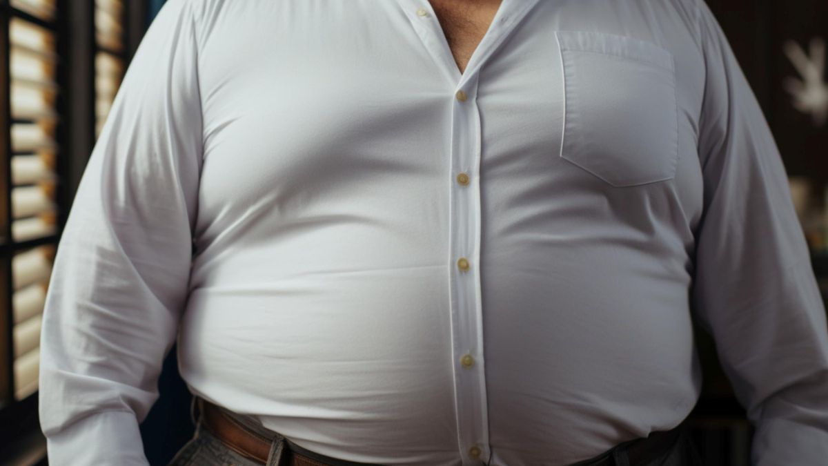 Uomo con camicia bianca tirata sulla pancia, simbolo di grasso addominale e problemi di salute.