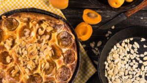 Crostata dorata con albicocche fresche e mandorle a lamelle, servita su piatto estivo