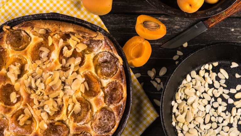Crostata dorata con albicocche fresche e mandorle a lamelle, servita su piatto estivo